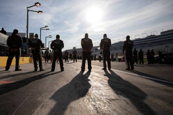 Race participants stand socially distanced as the national anthem plays before the NASCAR Xfini ...