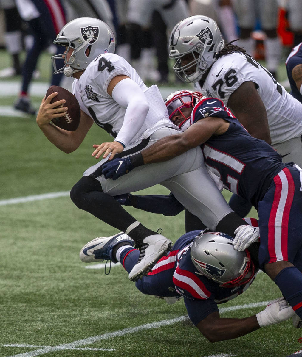 Las Vegas Raiders quarterback Derek Carr (4) is tackles by New England Patriots defensive back ...