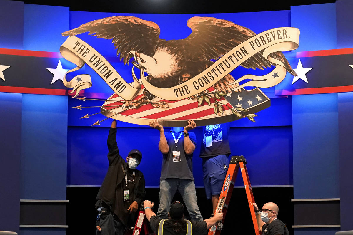 Workers adjust signage as preparations take place for the first Presidential debate in the Shei ...
