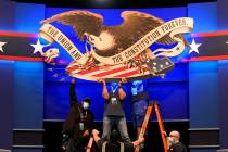 Workers adjust signage as preparations take place for the first Presidential debate in the Shei ...