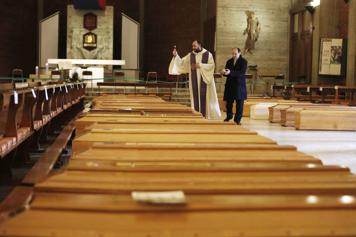 In this March 28, 2020, file photo, Don Marcello Crotti, left, blesses the coffins with Don Mar ...