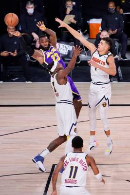 Los Angeles Lakers' LeBron James (23) passes the ball away from Denver Nuggets' Jerami Grant (9 ...