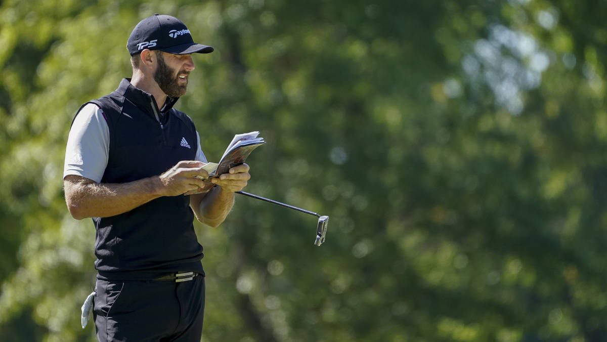 Dustin Johnson, of the United States, checks his notes on the fifth green during the third roun ...