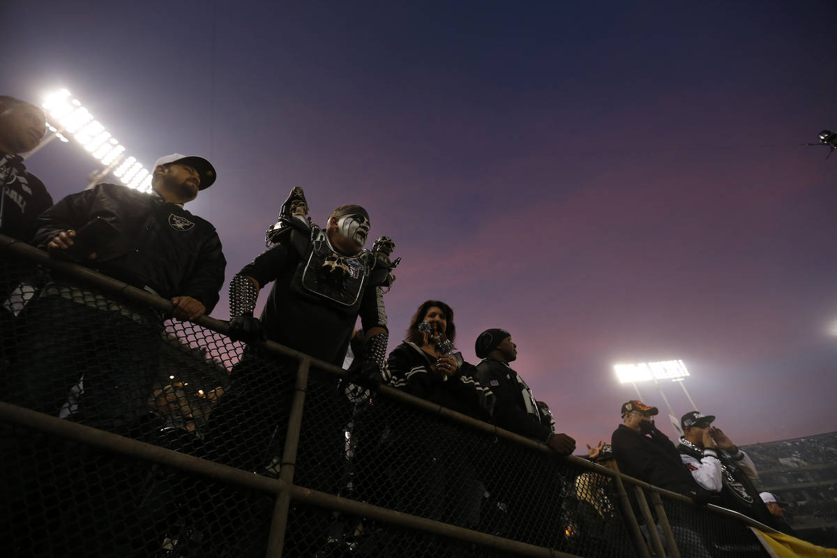 Fans watch as players warm up before an NFL football game between the Oakland Raiders and the L ...