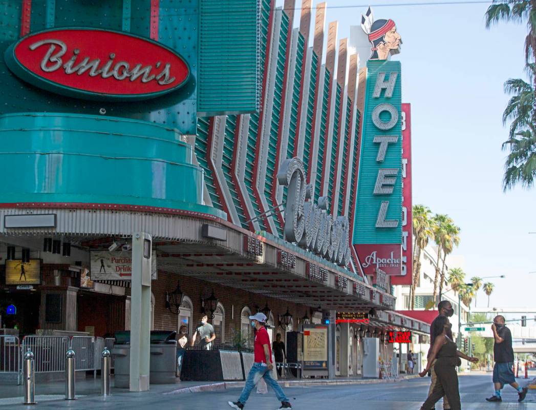 People walk across Fremont Street with Hotel Apache in the background in downtown Las Vegas on ...