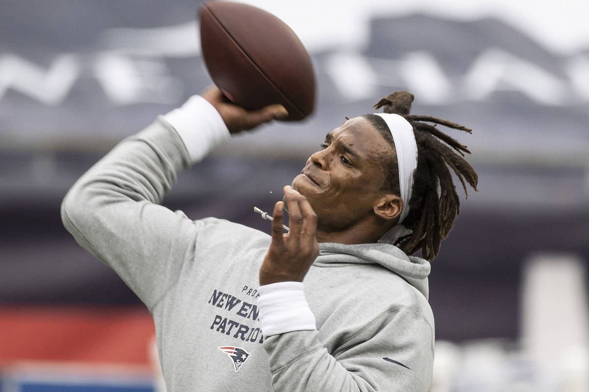 New England Patriots quarterback Cam Newton, left, warms up before the start of an NFL football ...