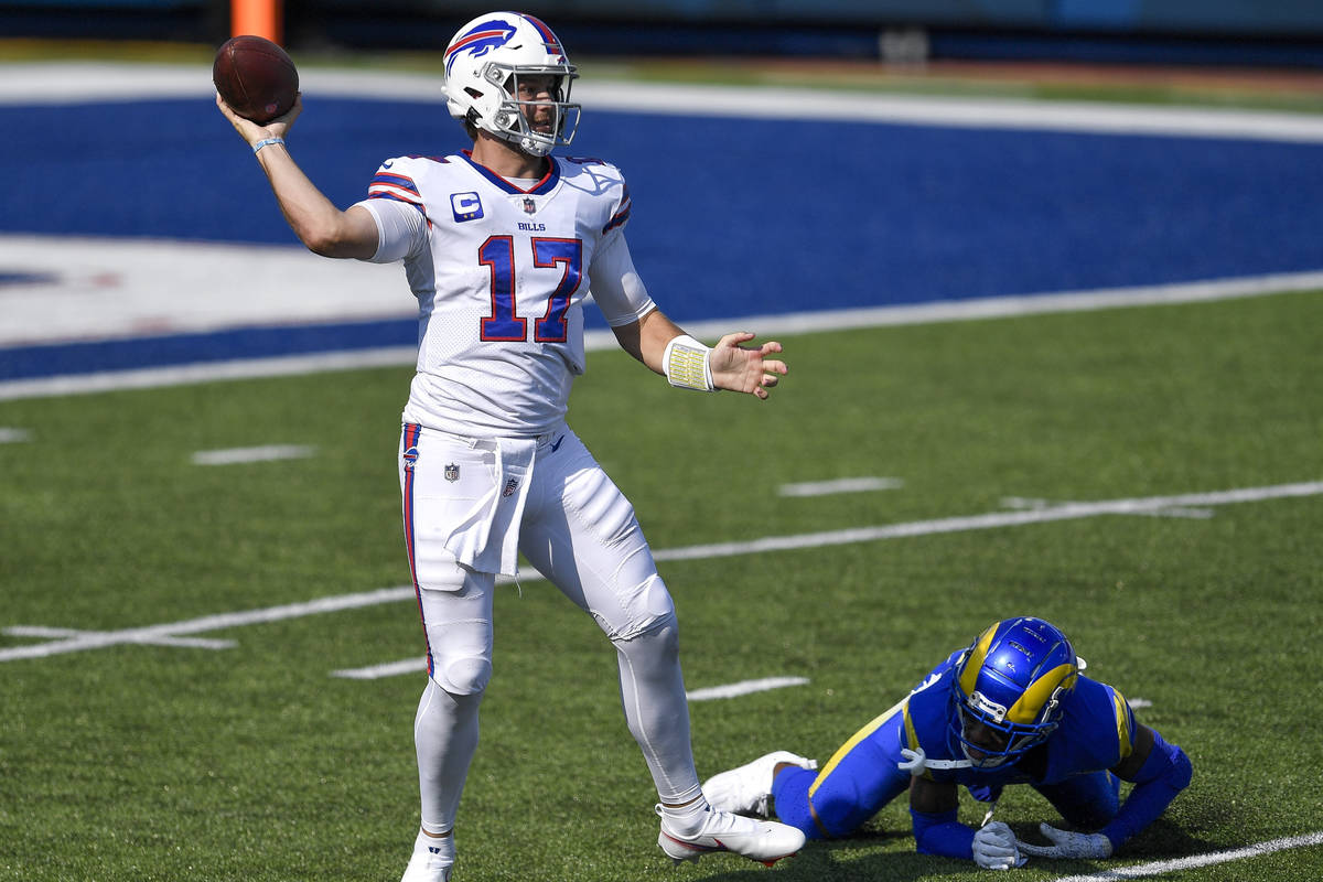 Buffalo Bills quarterback Josh Allen, left, throws a pass after avoiding a tackle by Los Angele ...