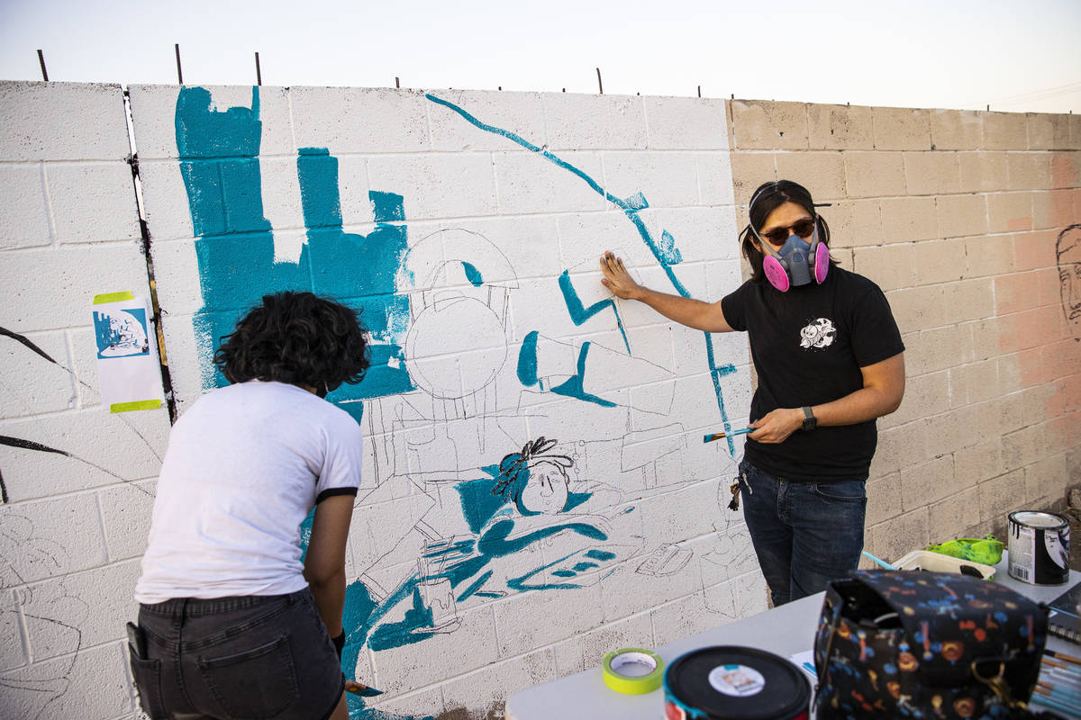 Artist Ross Takahashi, right, talks about his mural as he works alongside Dominique Chavira at ...