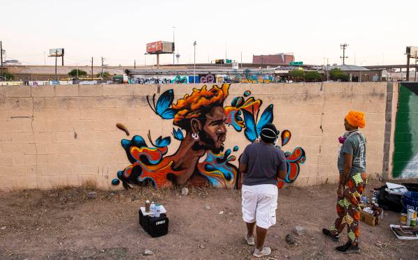 Artist Sloane Siobhan, of Las Vegas, looks at her mural "Butterfly Boy" alongside wif ...