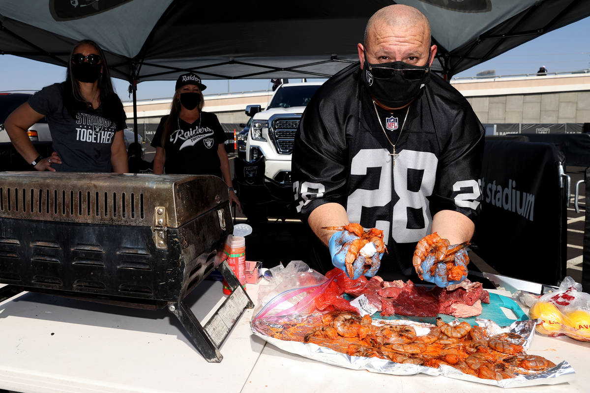 Omar Vivas of Palm Springs, Calif., prepares food for a barbecue during a tailgate event before ...