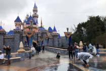 FILE - In this March 13, 2020 file photo, visitors take photos at Disneyland in Anaheim, Calif. ...