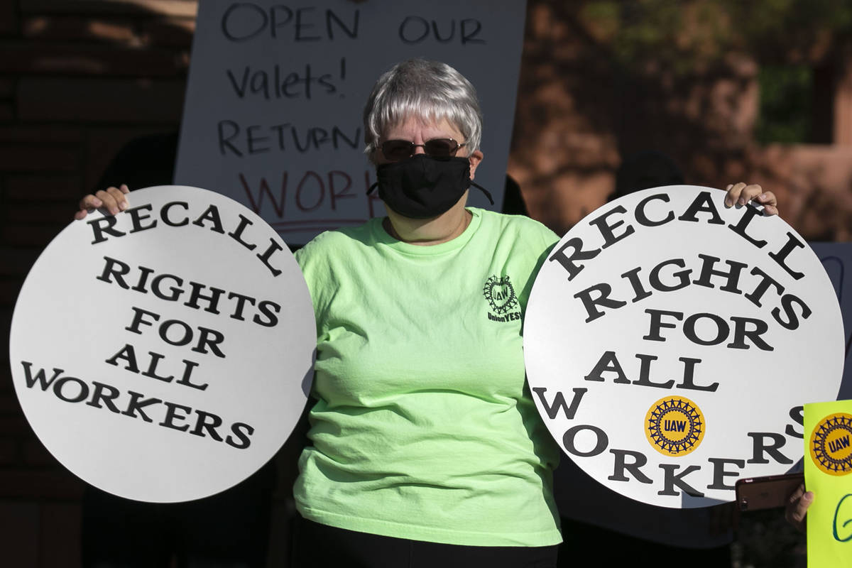 Paula Schusster, a dealer at Flamingo, holds signs as she joins a rally outside of the Clark Co ...