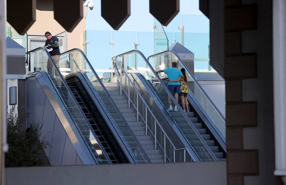 A worker performs scheduled maintenance on an escalator for the pedestrian bridge between Excal ...