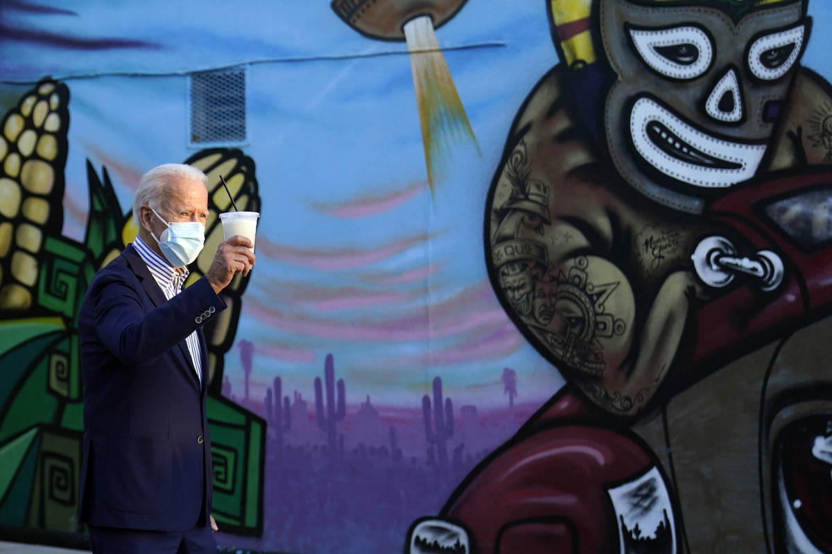 Democratic presidential candidate former Vice President Joe Biden holds up a drink he received ...