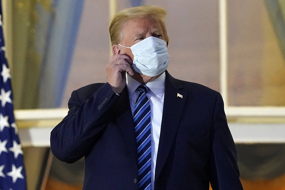 President Donald Trump removes his mask as he stands on the balcony outside of the Blue Room as ...