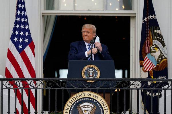 President Donald Trump removes his face mask to speak from the Blue Room Balcony of the White H ...