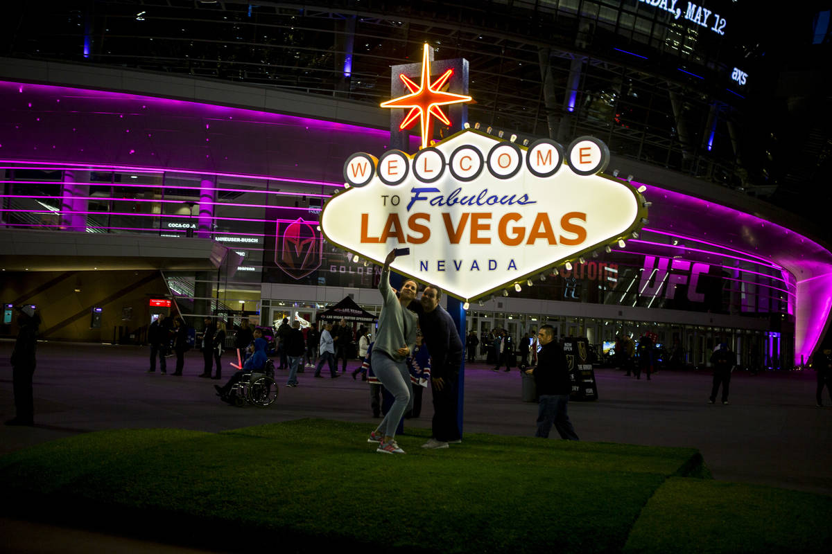 Pep rally attendees take photos with a scale model of the Las Vegas sign on Toshiba Plaza outsi ...