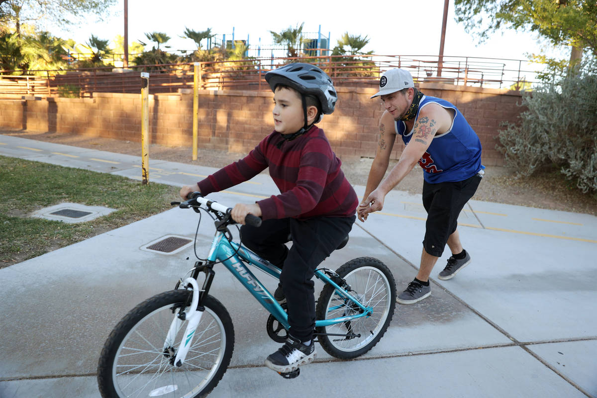Corey Behm helps his son Jason, 8, ride his bike around the Centennial Hills Park playground in ...