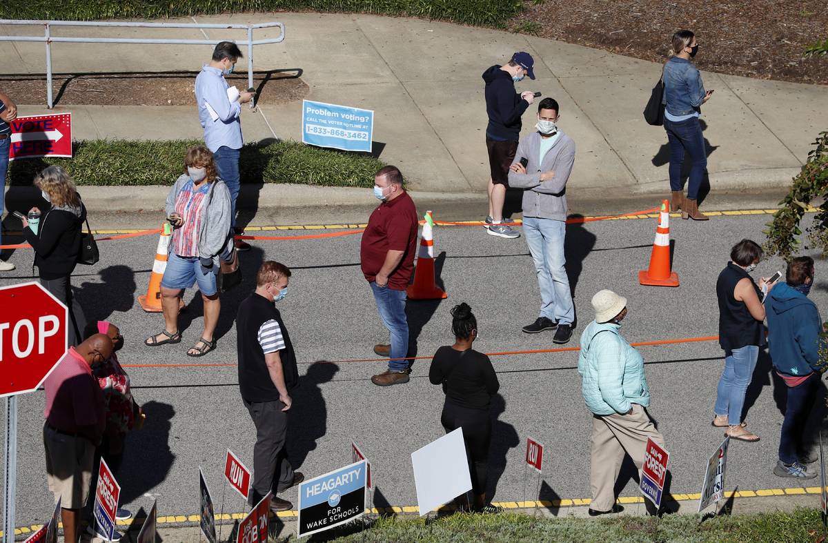 Voters wait in line outside the Herbert C. Young Community Center in Cary, N.C. on the first da ...