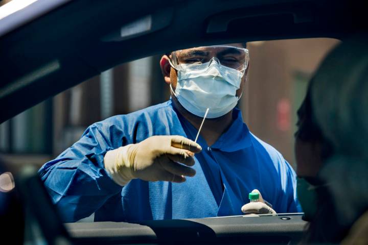 Practice Manager Jose Tirana conducts a COVID-19 test on a patient in the parking lot at Sahara ...