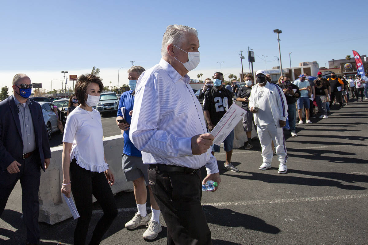 Gov. Steve Sisolak and his family walk into the Boulevard Mall early voting location to drop of ...