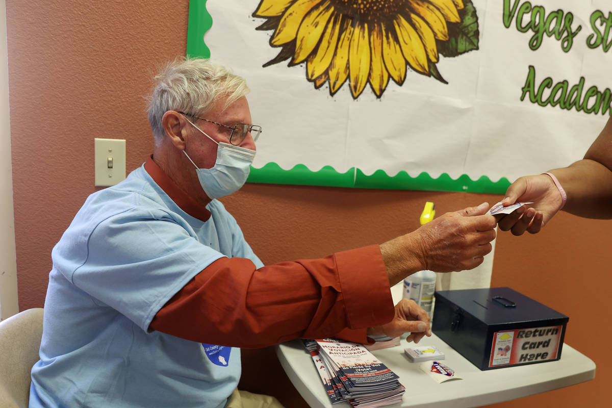 Poll worker Michael Brower hands out stickers to voters at the East Las Vegas Community Center ...