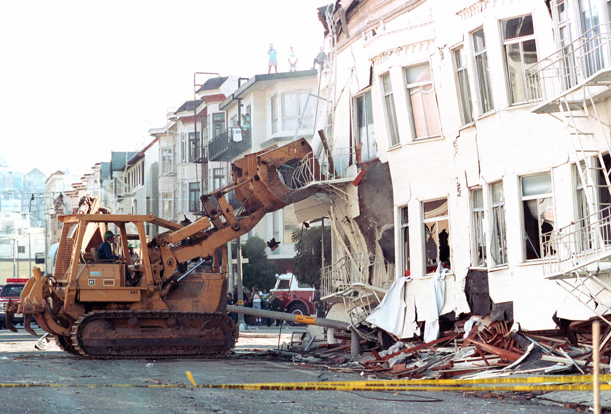 A bulldozer brings down a damaged apartment complex in the Marina district of San Francisco, Ca ...