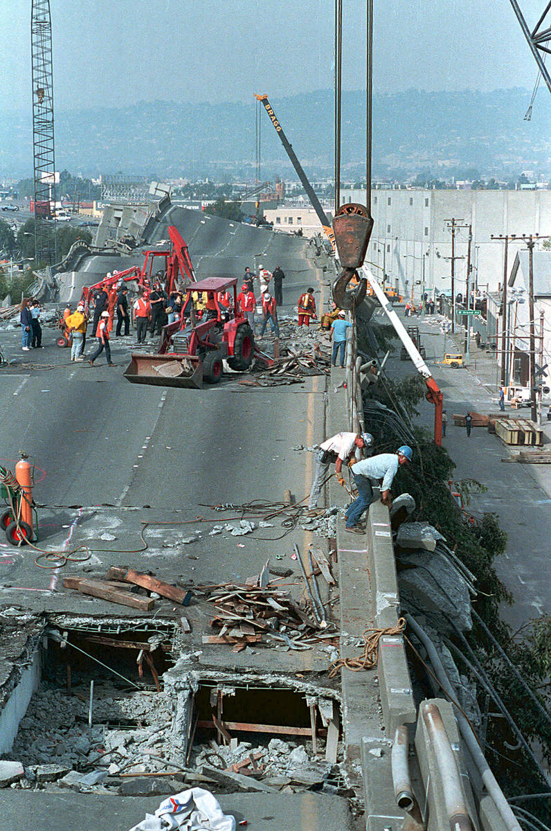 Heavy equipment cranes and backhoes probe and lift debris from the crushed Interstate 880 freew ...