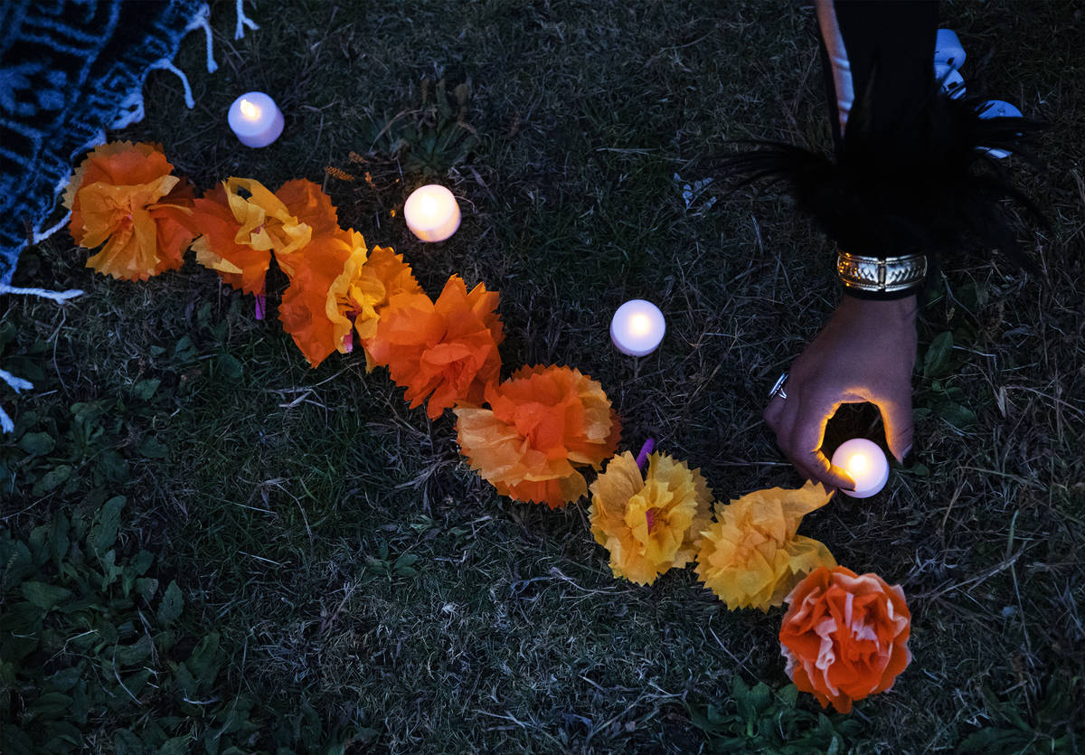 Ingrid ollintzihuatl Moctezuma sets out a candle at a Día de los Muertos event to honor pe ...