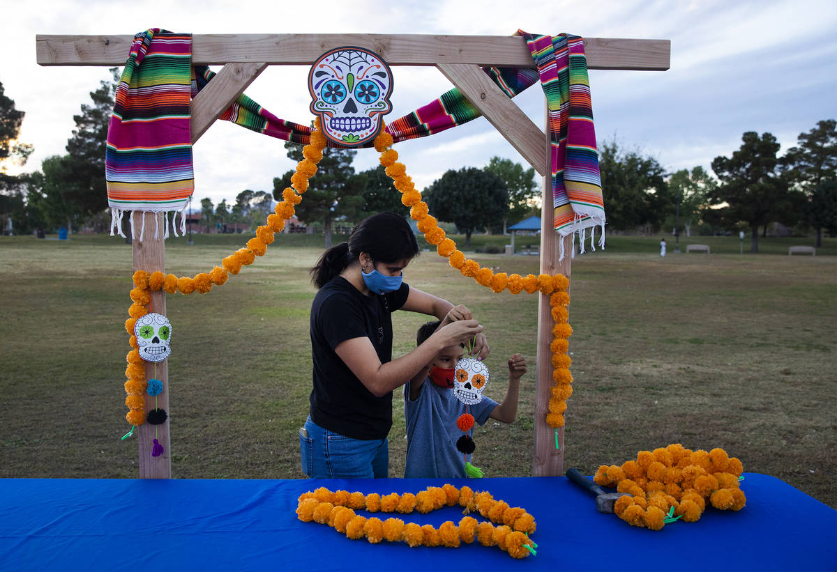 Ana Medina hangs a skull decoration with her son Freddy Medina, 6, at a Día de los Muertos ...
