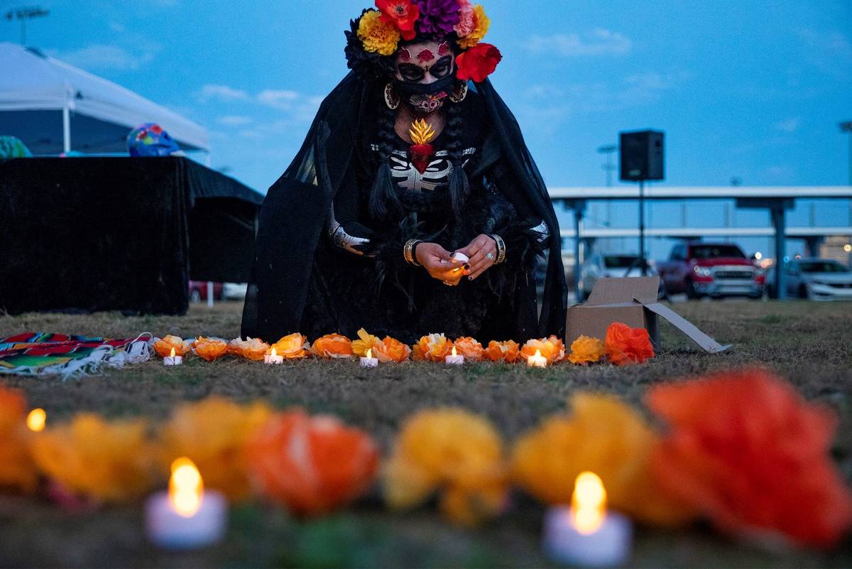 Ingrid ollintzihuatl Moctezuma sets out a candle at a Día de los Muertos event to honor people ...