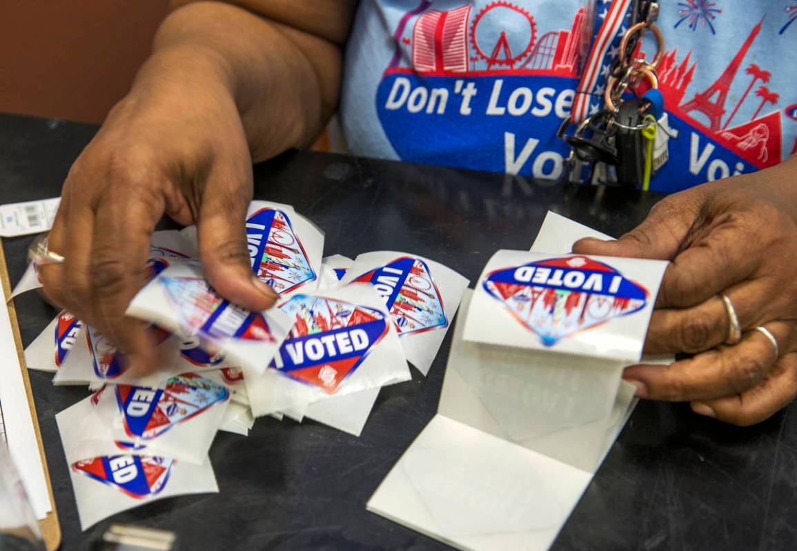 Elections worker Robin Wright readies "I Voted" stickers for mail-in ballot drop off voters dur ...