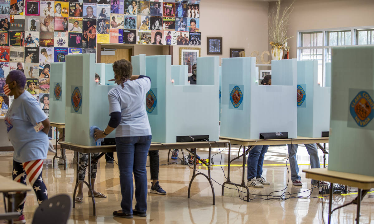 A volunteer assists a voter at a voting machine at the Doolittle Community Center voter center ...