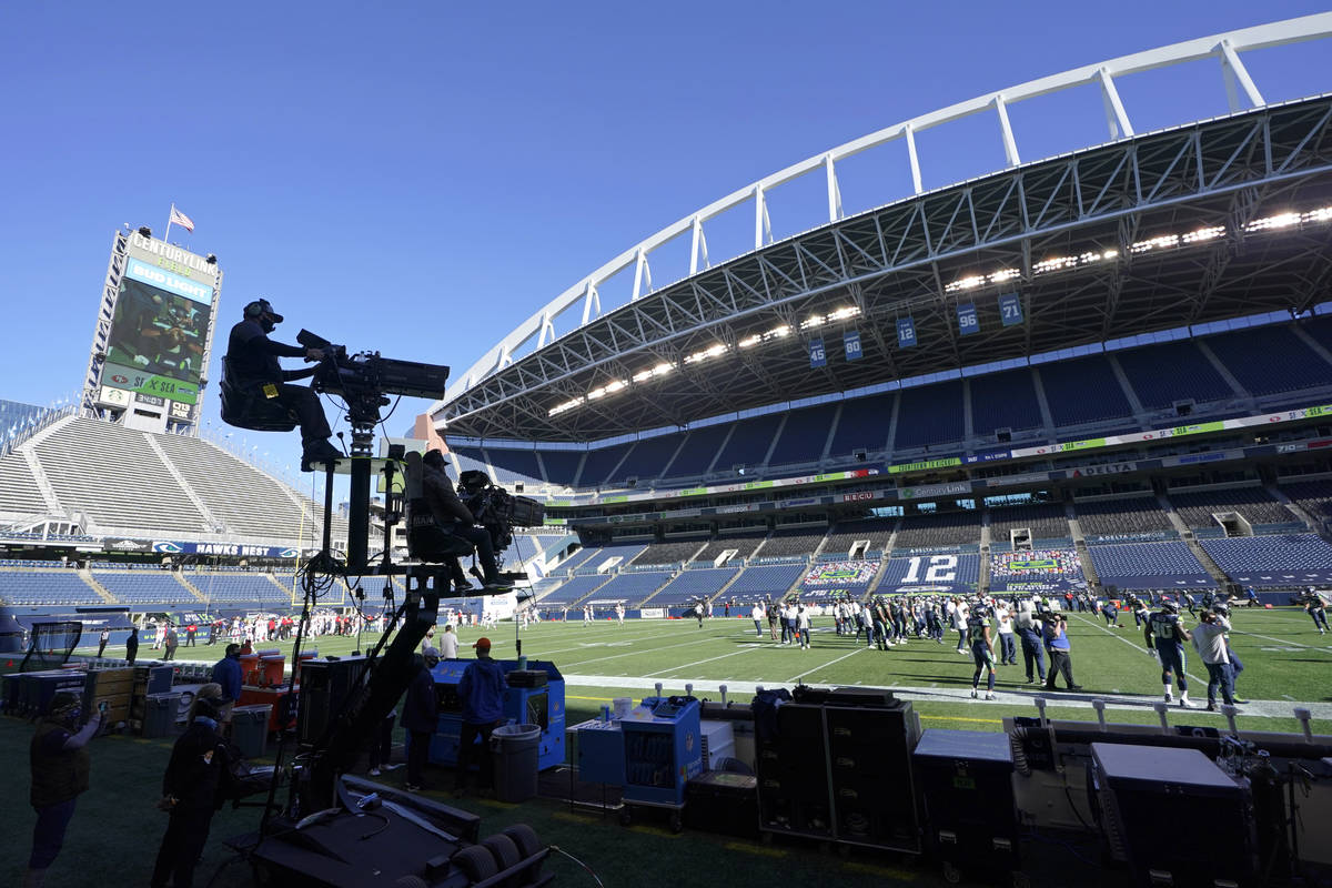 Two TV cameras mounted on a moving cart stand ready to capture action before an NFL football ga ...