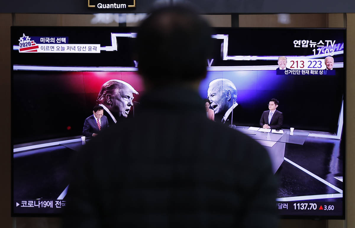 A man watches a TV screen showing the images of U.S. President Donald Trump and Democratic pres ...