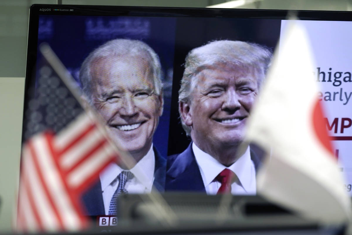 A Japanese and a U.S. flags are placed in front of a TV monitor showing a news program live bro ...