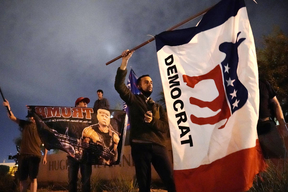 A supporter of Democrat Joe Biden waves a flag near supporters of President Trump in front of t ...