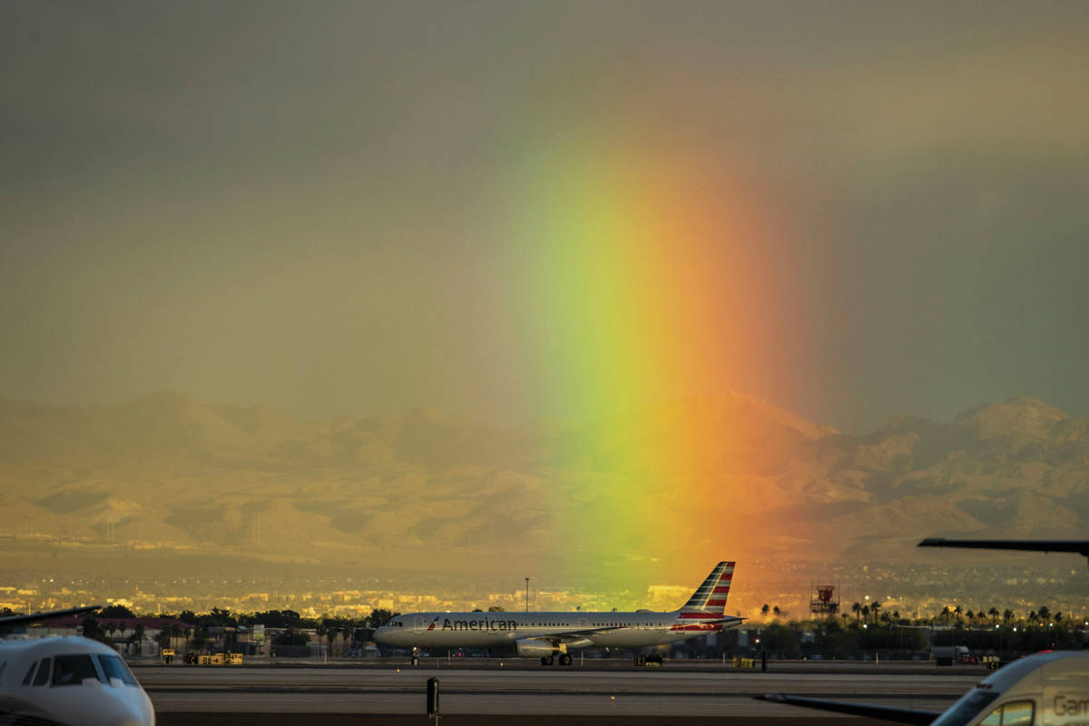 A rainbow shines bright behind McCarran International Airport as a car parade proceeds down the ...