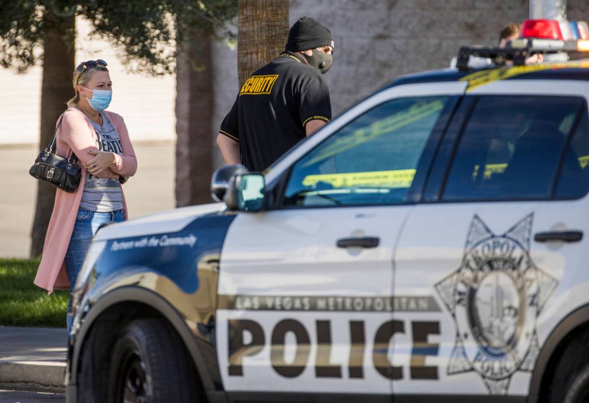 Individuals talk with Las Vegas police officers as they investigate a homicide in the central v ...