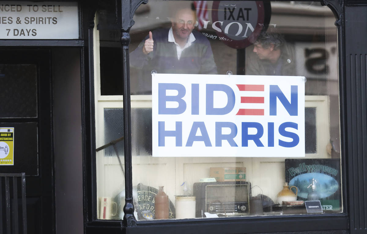 Derek Leonard gestures, behind a poster supporting Joe Biden in the town of Ballina, Ireland, S ...