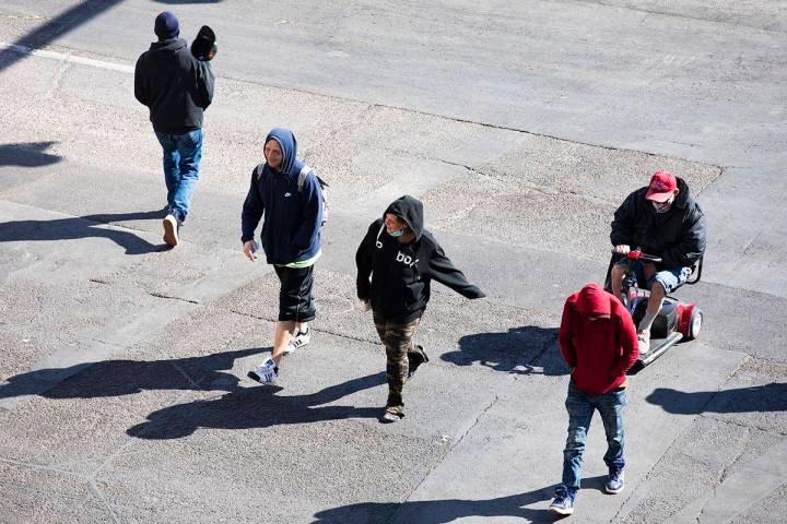 Visitors bundled in sweatshirts and jackets cross Las Vegas Boulevard at Fremont Street in Down ...