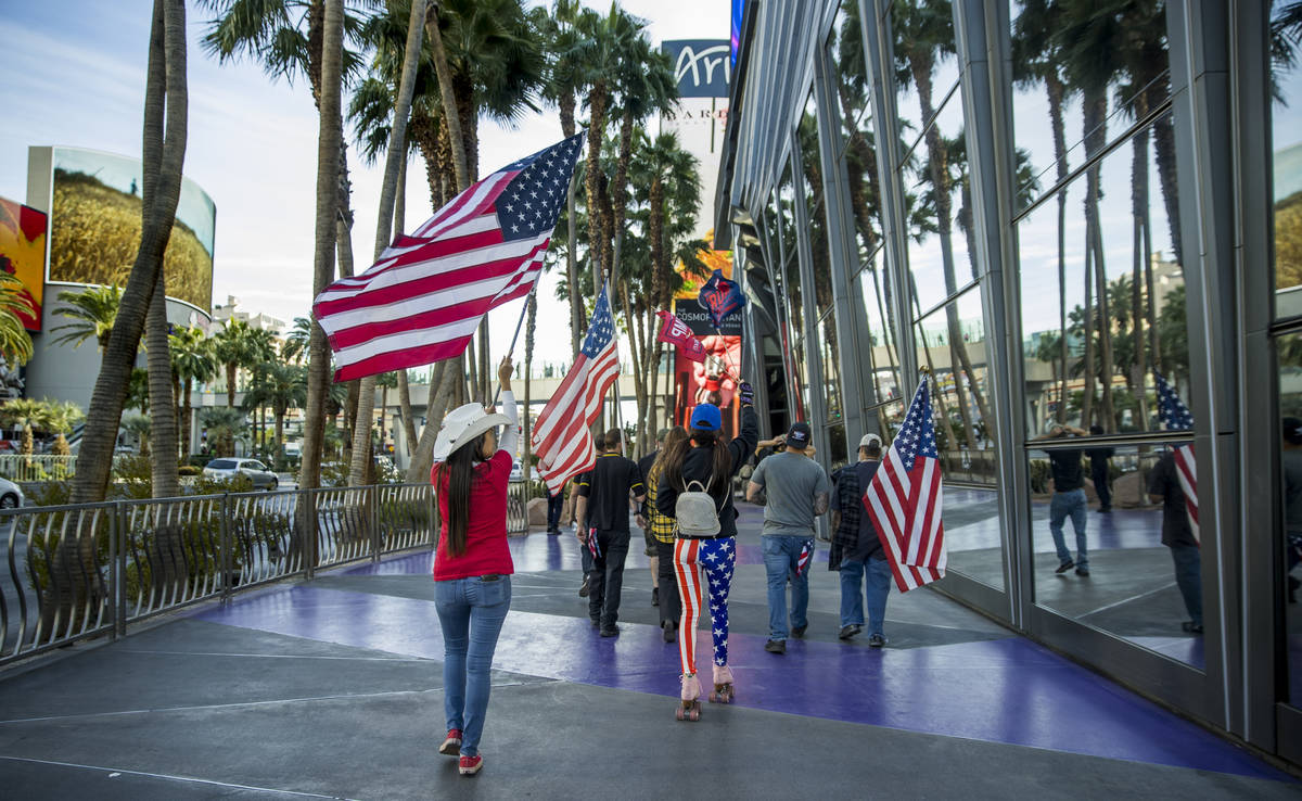 A group moves past The Cosmopolitan during a Veterans Day march to peacefully protest Governor ...