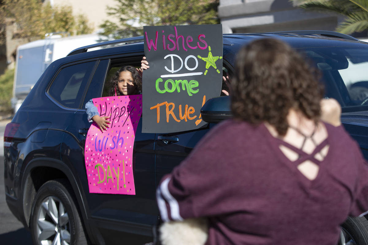 A car parade passes Las Vegan Lauren Cleveland, who received a new puppy from Make-A-Wish South ...