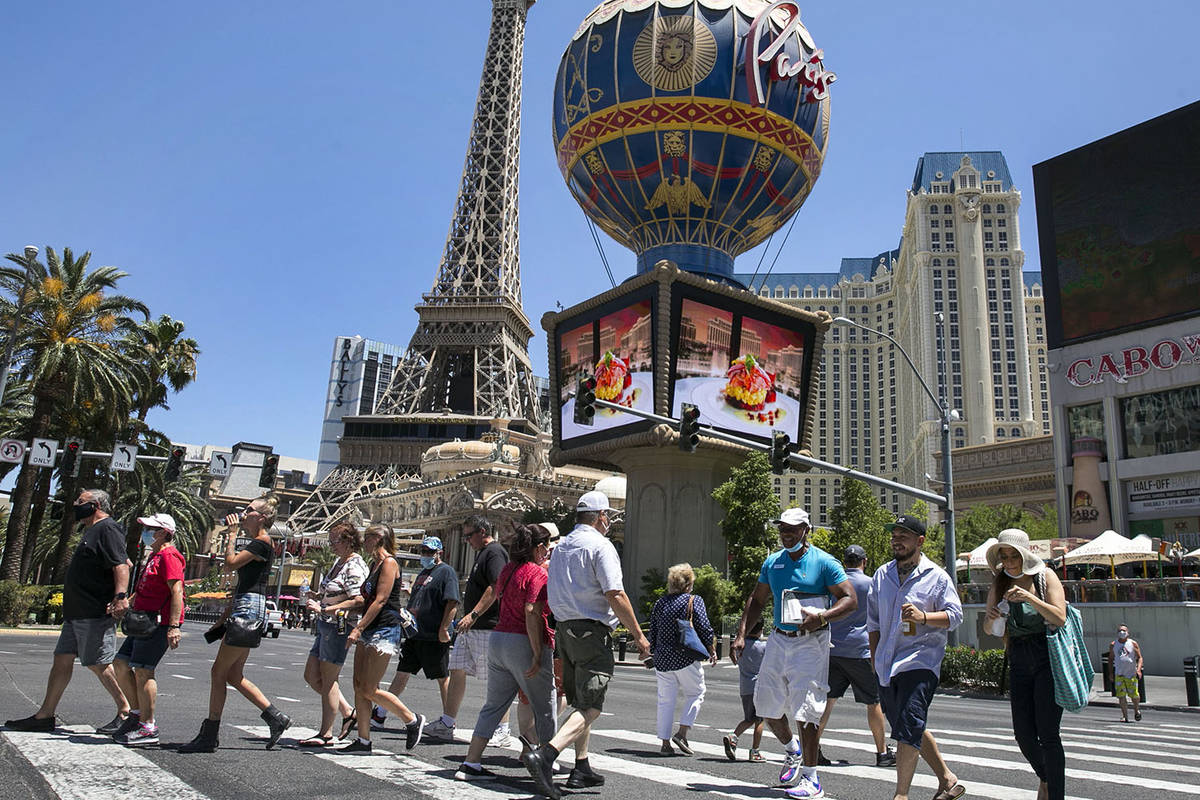 Tourists cross Las Vegas Boulevard near Paris hotel-casino on Friday, July 3, 2020, in Las Veg ...