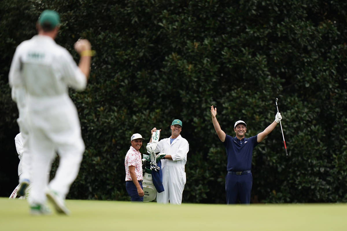 Rickie Fowler, left, watches as Jon Rahm celebrates after making a hole-in-one on the 16th hole ...