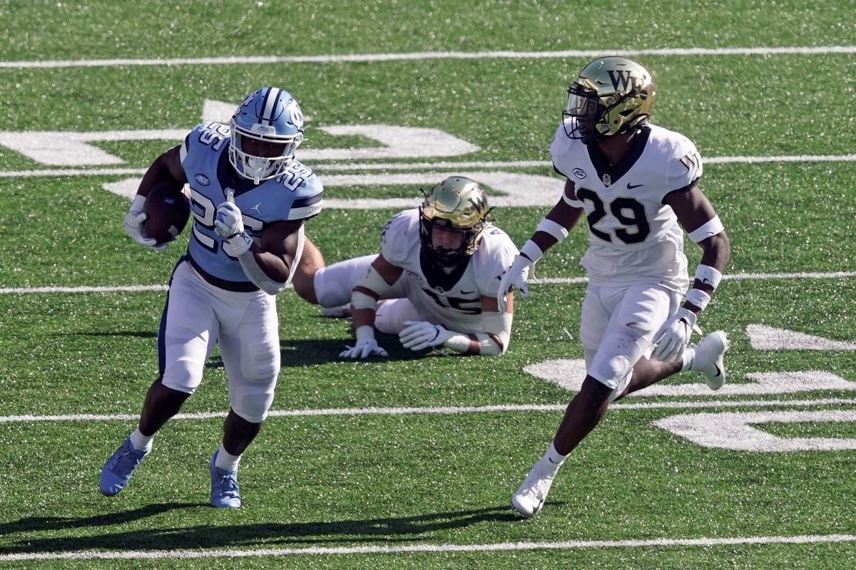 North Carolina running back Javonte Williams (25) runs while Wake Forest defensive back Caelen ...