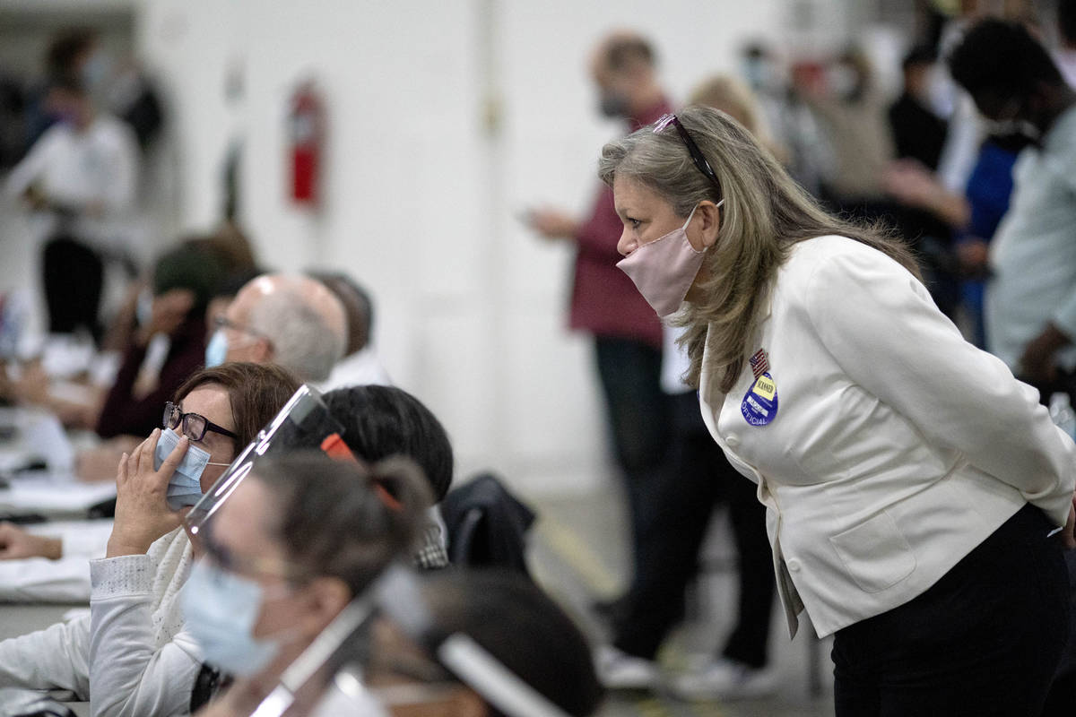 FILE - In this Nov. 4, 2020 file photo, a Republican election challenger at right watches over ...