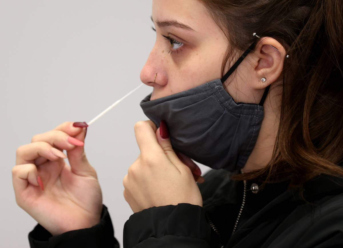 Karina Lewis of Las Vegas uses a nasal swab for a COVID-19 test on the first day of testing ope ...