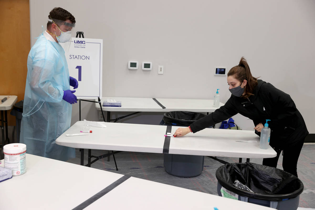 Karina Lewis of Las Vegas returns a nasal swab COVID-19 test to Isaac Nielson, a supervisor at ...