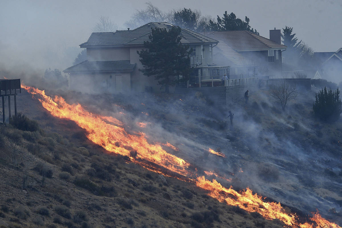 People try to protect their homes during the Pinehaven Fire in the Caughlin Ranch area of Reno ...
